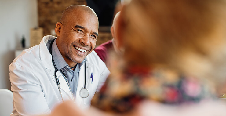 Smiling doctor in focus with patient blurred out