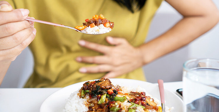 Woman getting heartburn from her spicy food