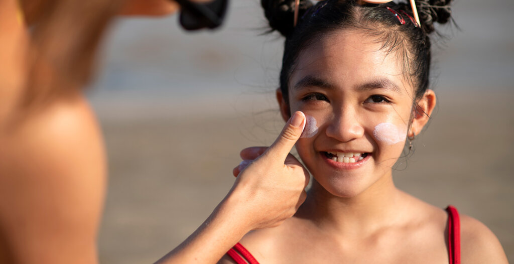 Little girl with sunscreen being applied to her cheeks