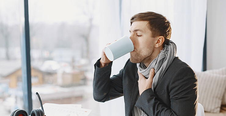Young man drinking tea for a sore throat